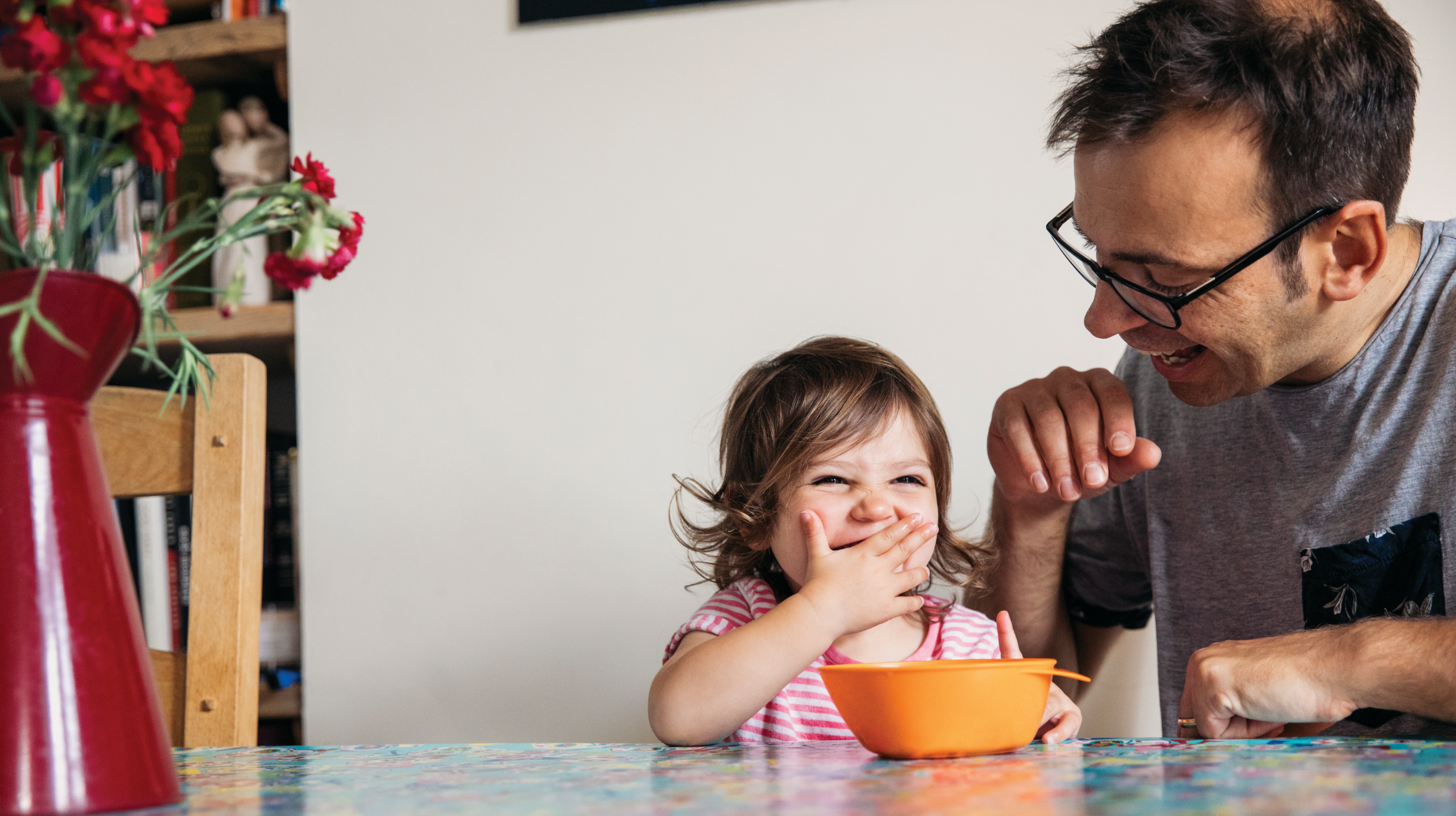 child eating form bowl and laughing with father