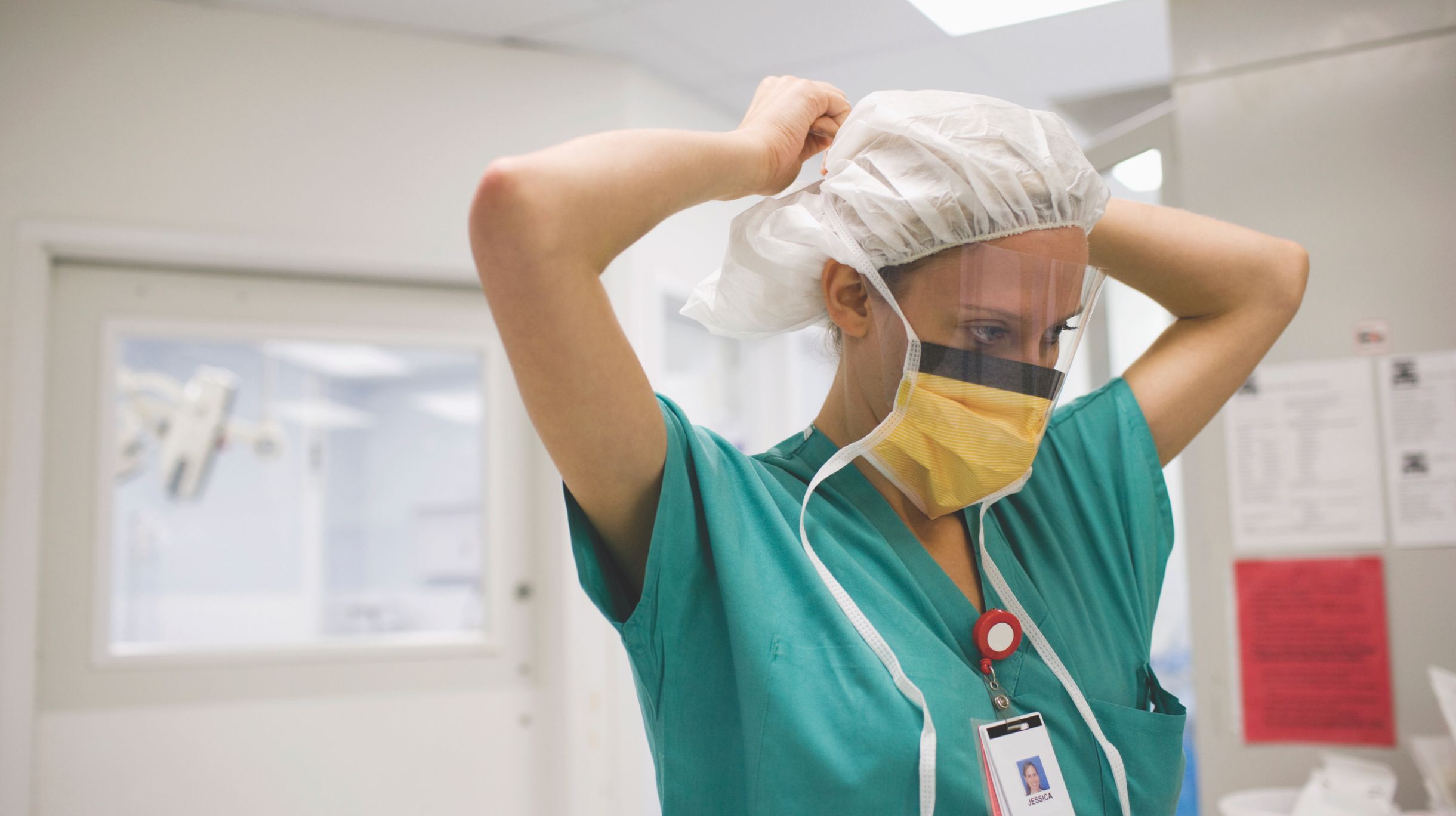 Doctor in hospital putting on personal protective gear