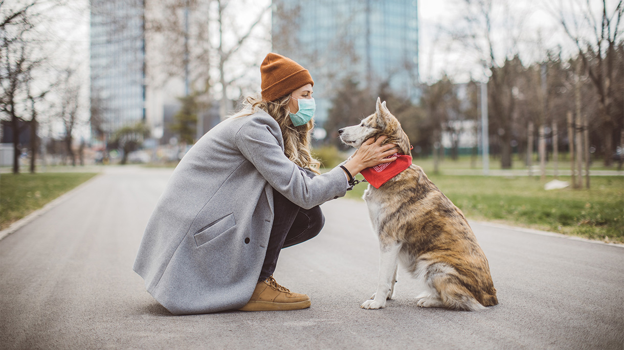 Woman with mask outside with dog