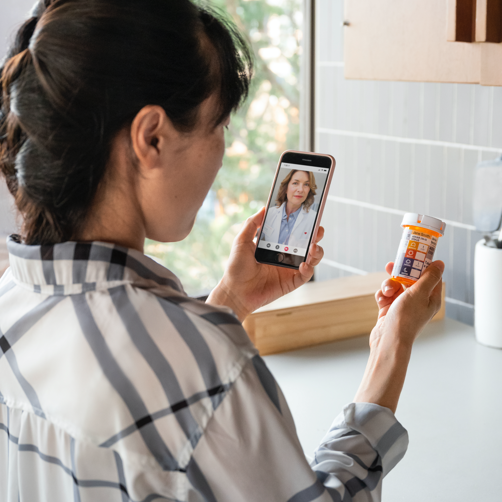 back of a woman's head video chatting with doctor holding prescription bottle