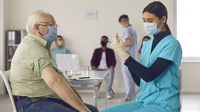 Nurse preparing vaccine for elder man