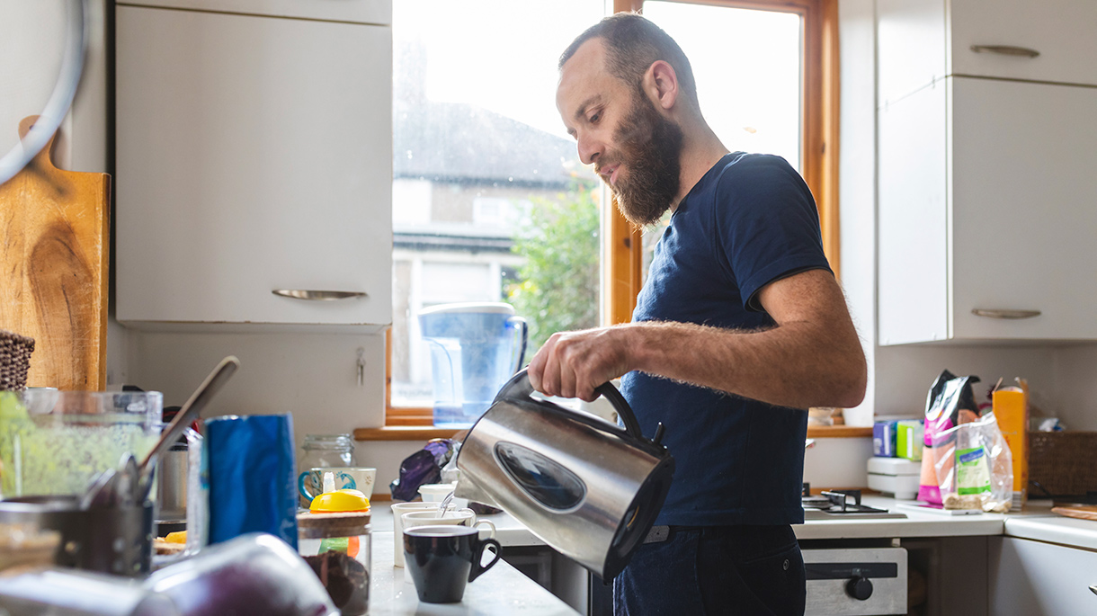 Man pouring hot water from kettle into mugs