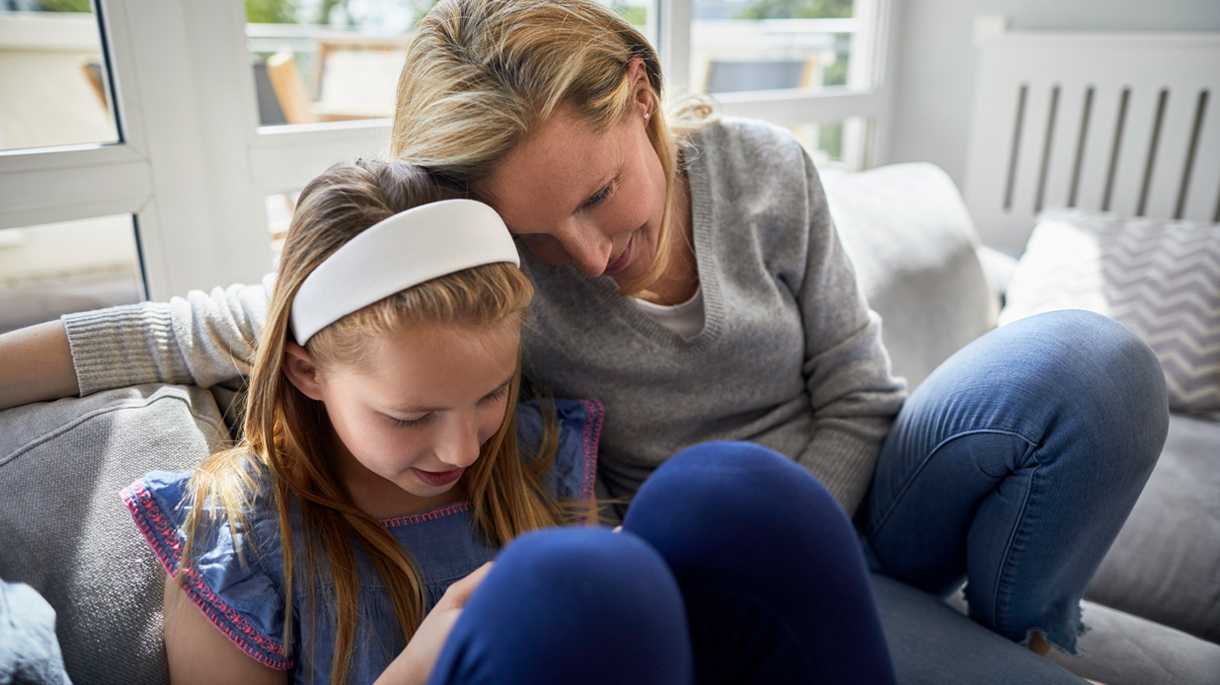 Young girl on mobile device with parent