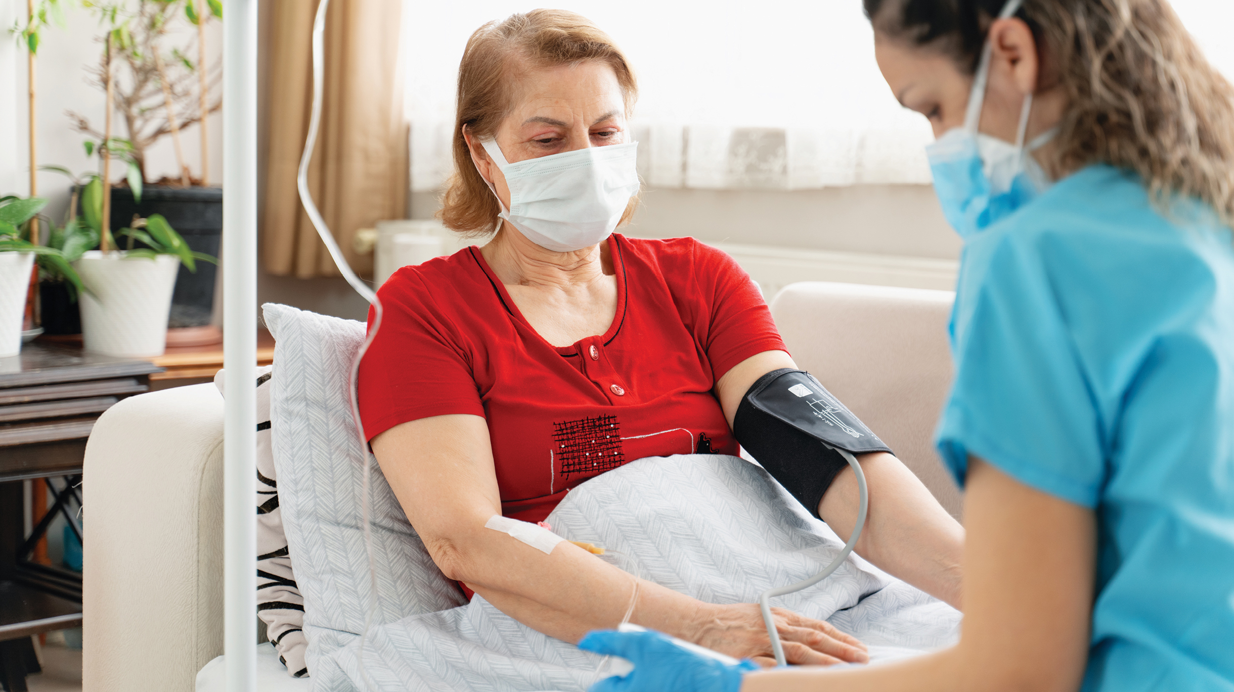 Masked woman sitting in chair being cared for by a masked nurse