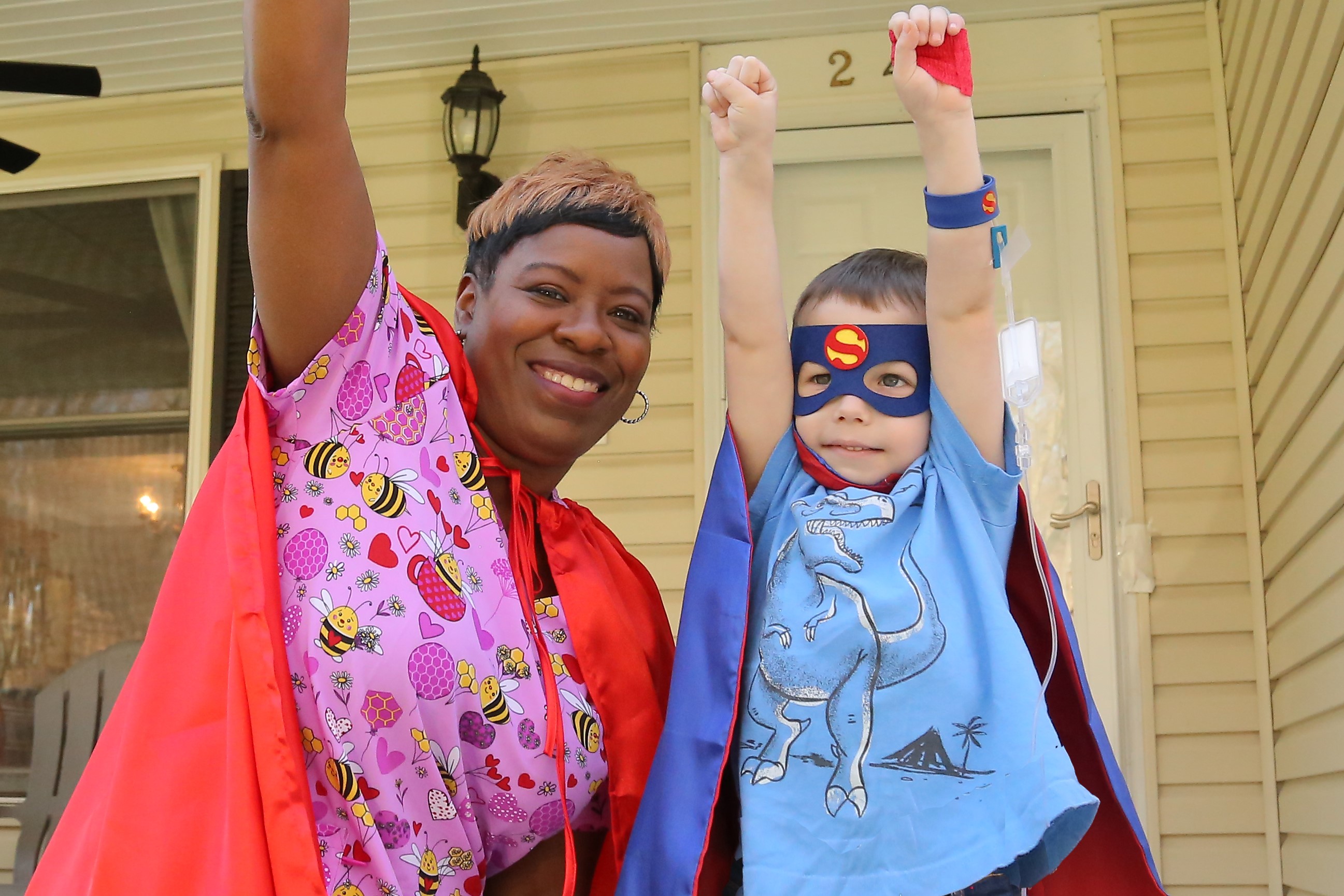 Coram Nurse Sharon and her 4-year-old patient wearing superhero capes